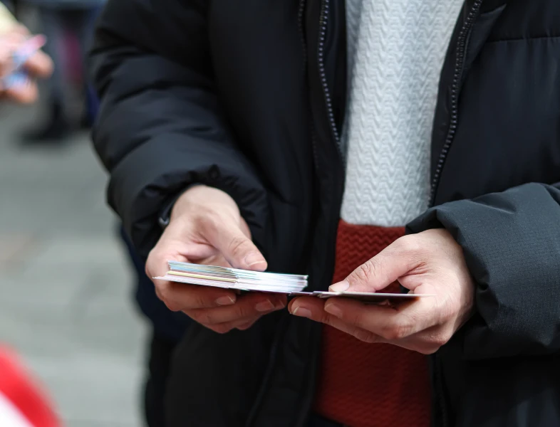 Person in winter coat holding cards
